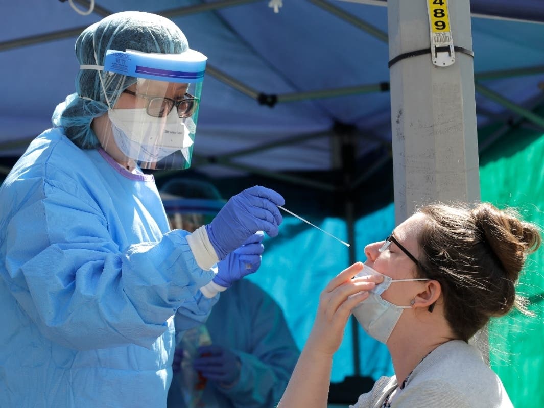 Tina Nguyen (left), a nurse at the International Community Health Services clinic in Seattle's International District, takes a nose swab sample from Mindy Balk, an ICHS employee, during walk- and drive-up testing for COVID-19.