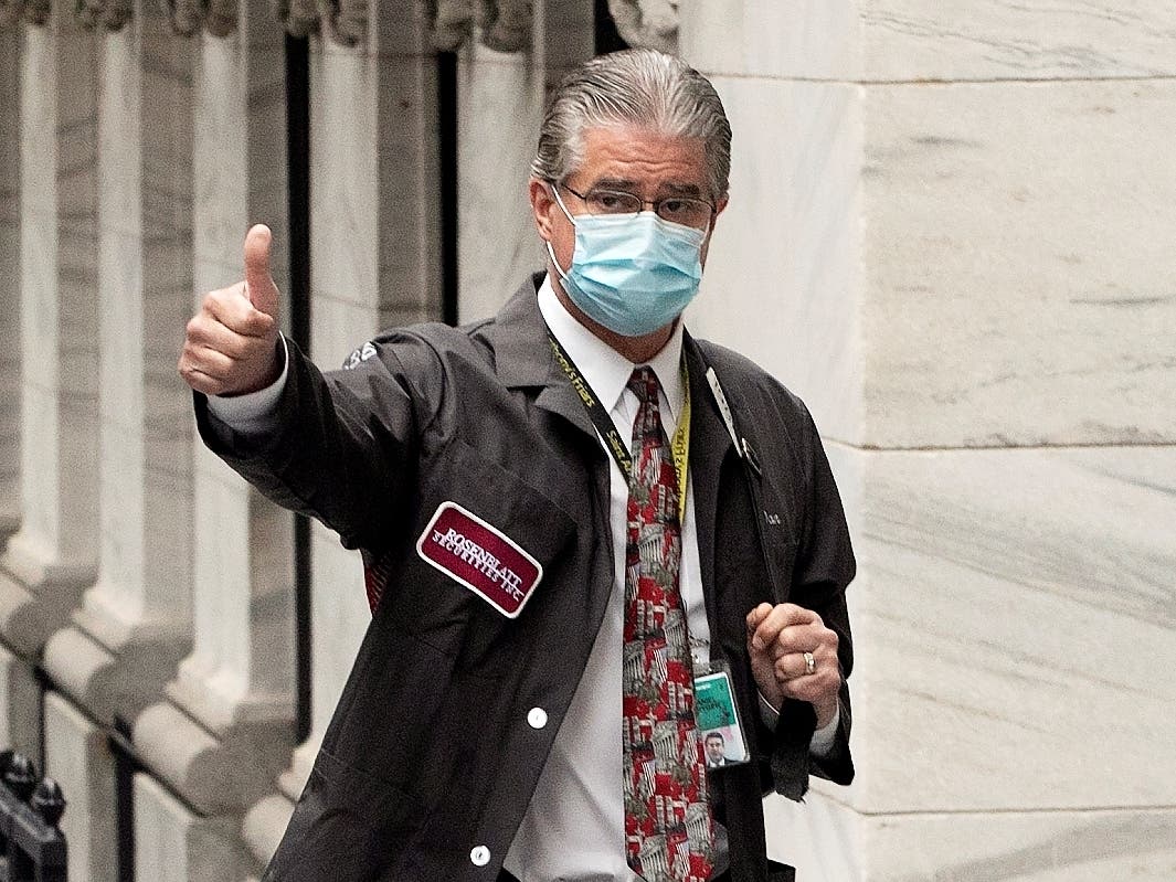 Trader Daniel Krieger gives a thumbs-up signal Tuesday as he arrives at the New York Stock Exchange, whose trading floor is reopening.