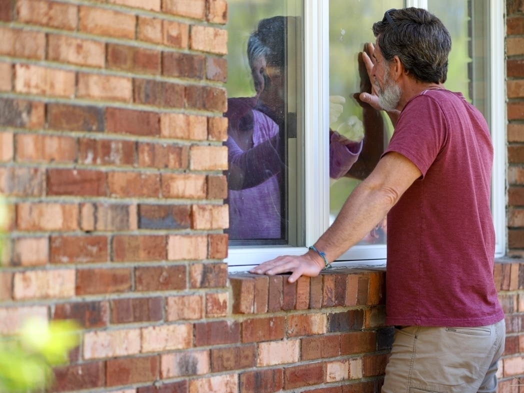 Jack Campise and his mother, Beverly Kearns, talk through her apartment window at a Connecticut nursing home.  A new federal report shows more than 60,000 nursing home residents have contracted COVID-19 and nearly 26,000 have died.