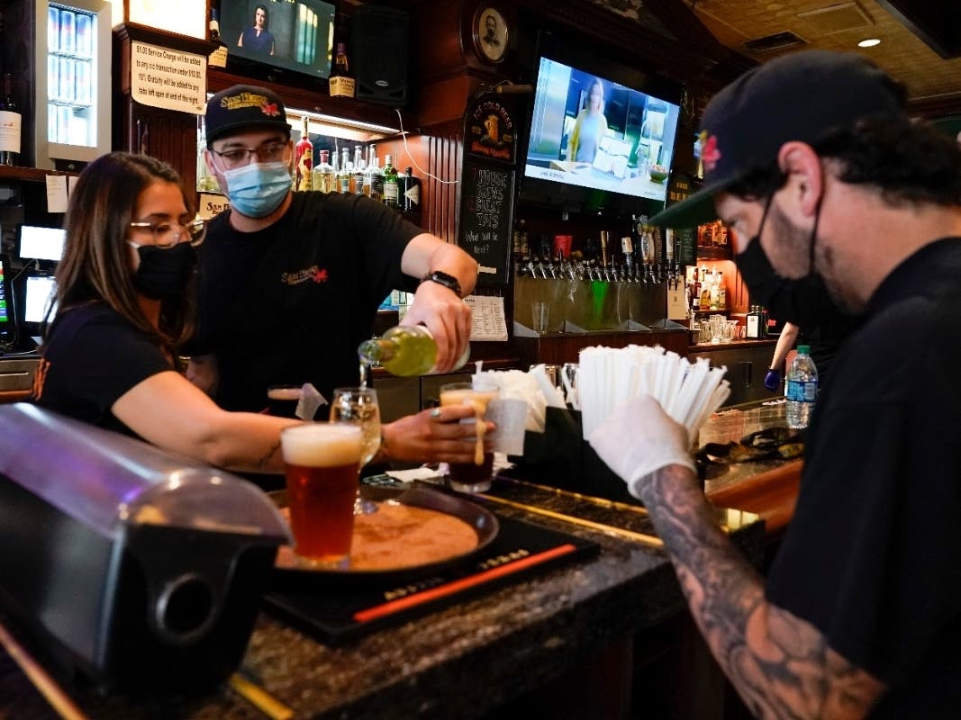 Workers mix drinks while wearing face masks at the bar at San Pedro Brewing Company in the San Pedro area of Los Angeles. 