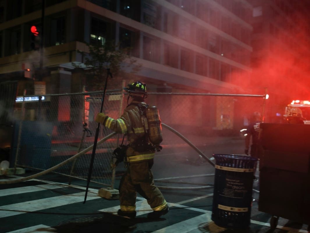 Firefighters put out a dumpster fire as protesters and police gather at Lafayette Park near the White House in Washington on Monday, June 22, after protesters tried to topple a statue of Andrew Jackson before being dispersed by police.