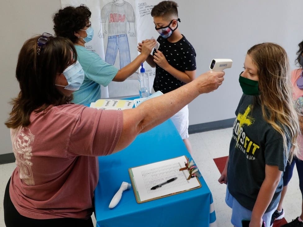Amid concerns of the spread of COVID-19, science teachers Ann Darby, left, and Rosa Herrera check-in students before a summer STEM camp at Wylie High School in Wylie, Texas.