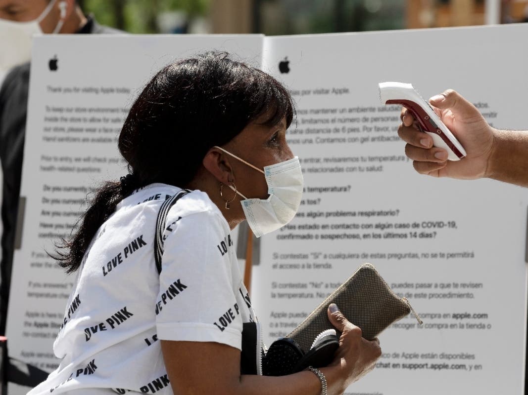 A customer has her temperature checked before entering the Apple Store in Boston. 