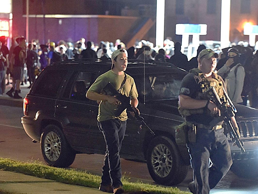 Kyle Rittenhouse, left, with backwards cap, walks along Sheridan Road in Kenosha Tuesday, Aug. 25 with another armed civilian. Prosecutors charged Rittenhouse, a 17-year-old from Illinois in the fatal shooting of two protesters and the wounding of a third