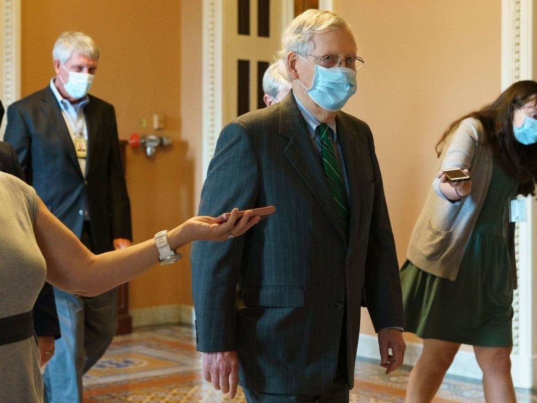 ​Senate Majority Leader Mitch McConnell of Kentucky, center, walks to his office from the Senate floor on Tuesday on Capitol Hill in Washington.