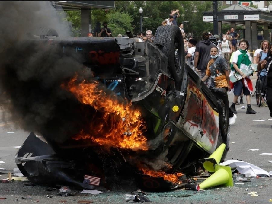 Protesters demonstrate as a Salt Lake City police vehicle burns, in Salt Lake City.