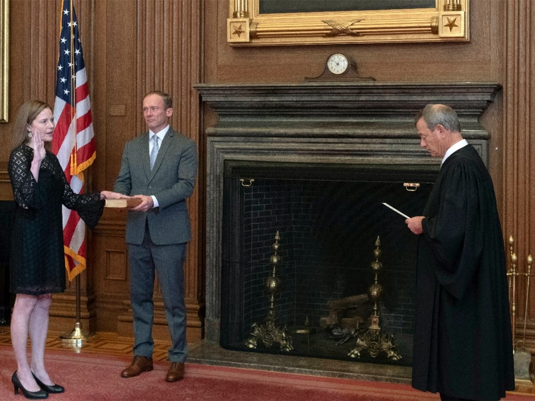 In this image provided by the Collection of the Supreme Court of the United States, Chief Justice John G. Roberts, Jr., right, administers the Judicial Oath to Judge Amy Coney Barrett in the East Conference Room of the Supreme Court Building.
