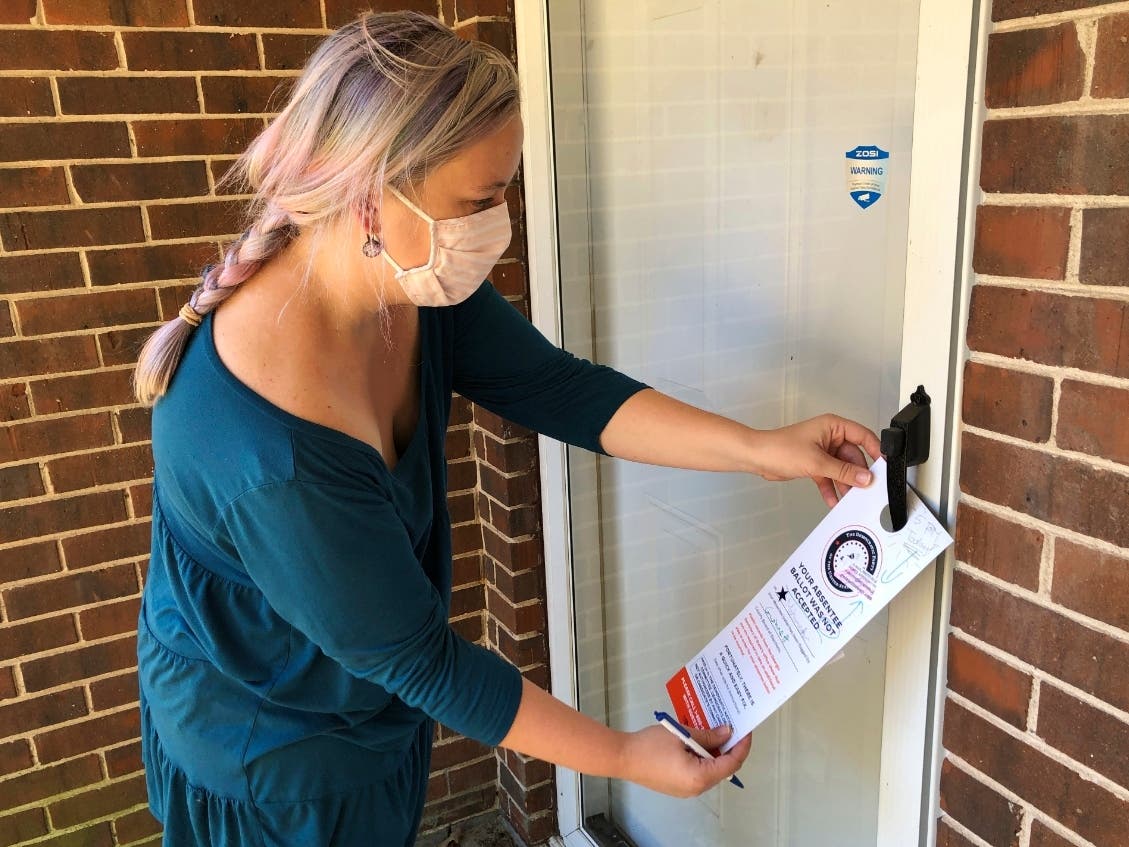 Christin Clatterbuck leaves an affidavit and information about fixing absentee ballots on the door of a home in Stone Mountain, Ga., on Friday.