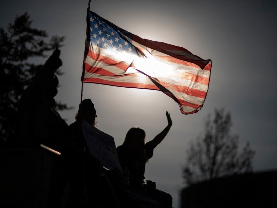 A Trump supporter holds an American flag while protesting against the election results outside the central counting board at the TCF Center in Detroit.