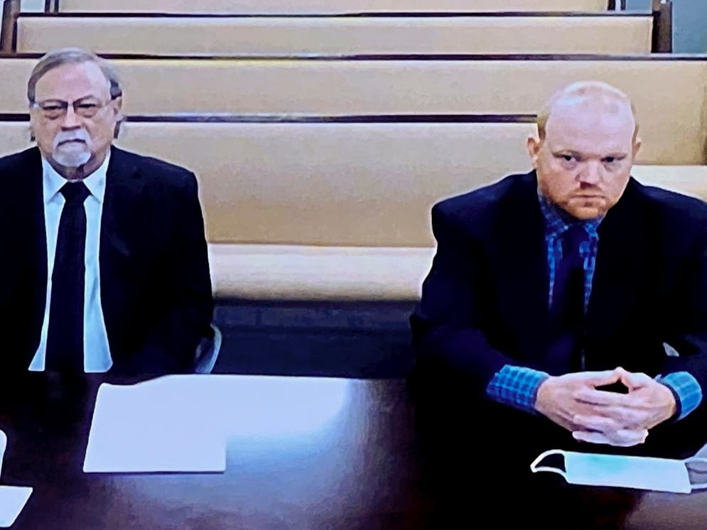 In this image made from video, from left, father and son, Gregory and Travis McMichael, accused in the shooting death of Ahmaud Arbery listen during a hearing held via closed circuit tv in the Glynn County Detention Center.