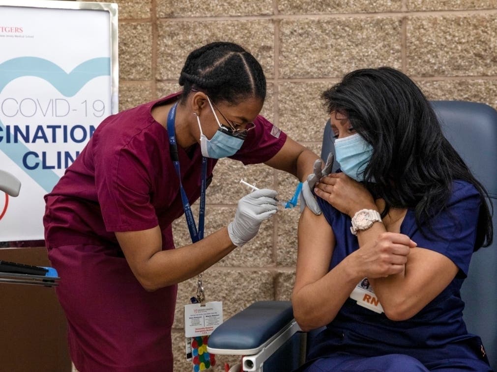 ​Nurse Maritza Beniquez, right, receives the Pfizer-BioNTech COVID-19 vaccine at University Hospital, in Newark, New Jersey, Tuesday. Beniquez was the first person in New Jersey to receive the vaccination.
