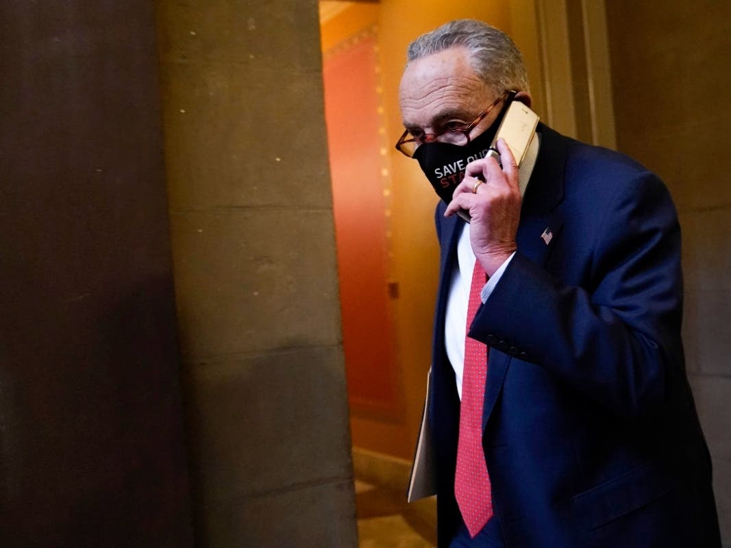 Senate Minority Leader Sen. Chuck Schumer of N.Y., walks on Capitol Hill in Washington, Tuesday as officials work out the details of a new COVID-19 relief bill.