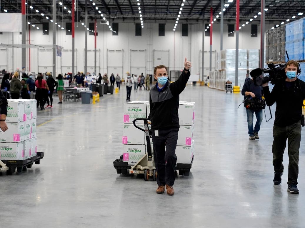 A worker gives a thumbs up while transporting boxes containing the Moderna COVID-19 vaccine to the loading dock for shipping at the McKesson distribution center in Olive Branch, Mississippi.