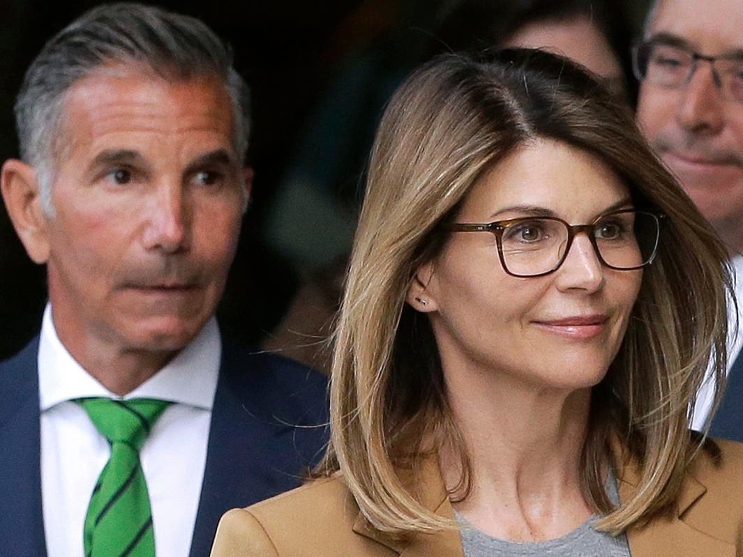 Actor Lori Loughlin, front, and husband, clothing designer Mossimo Giannulli, left, depart federal court in Boston after facing charges in a nationwide college admissions bribery scandal. Loughlin was released from federal prison after two months.