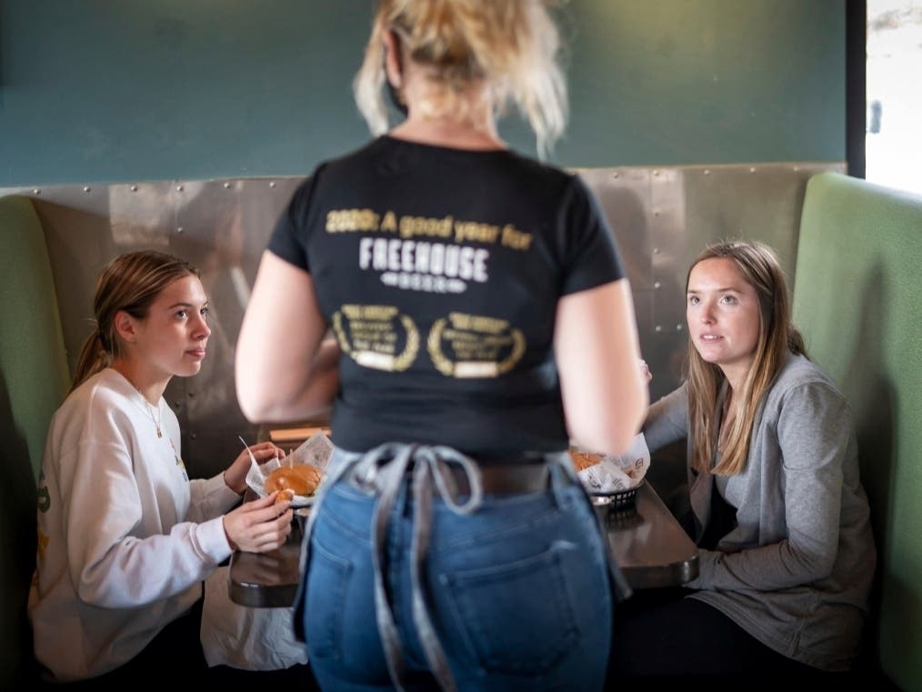 Grace Mathre, server at Longfellow Grill, checks on University of St. Thomas students Lindsey Schulz and Maren Daggett in Minneapolis on Monday.