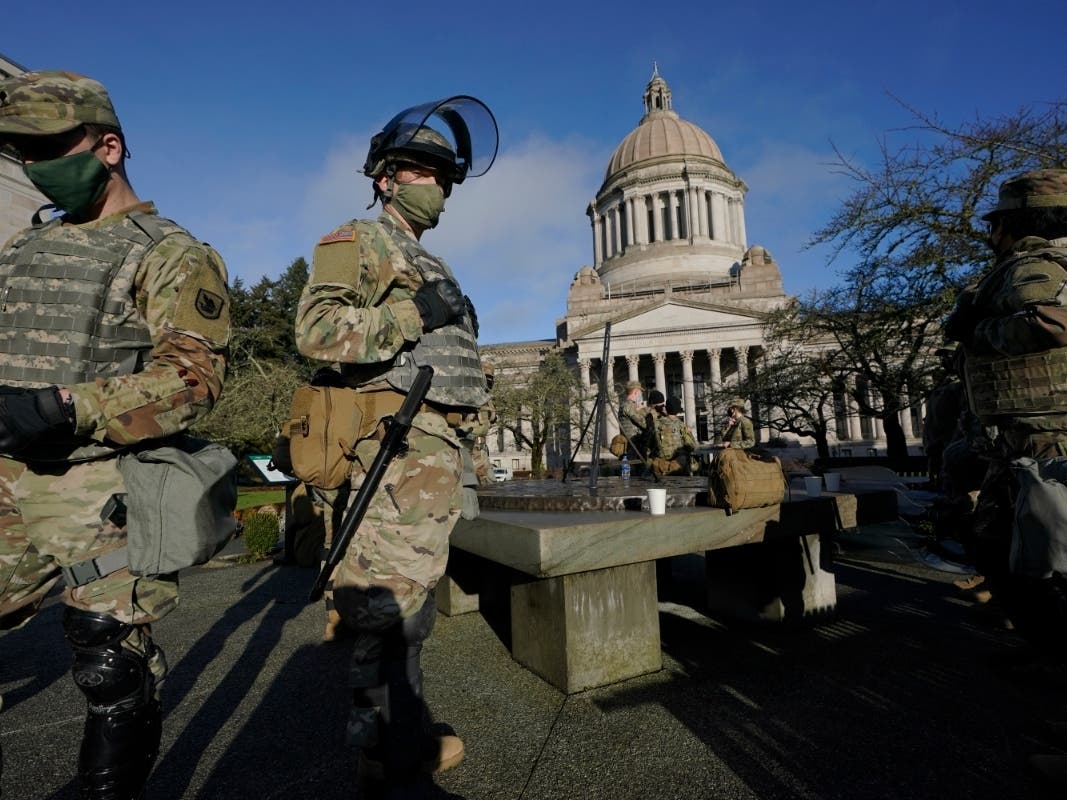 Members of the Washington National Guard stand at a sundial near the Legislative Building, Sunday, Jan. 10, 2021, at the Capitol in Olympia, Wash.