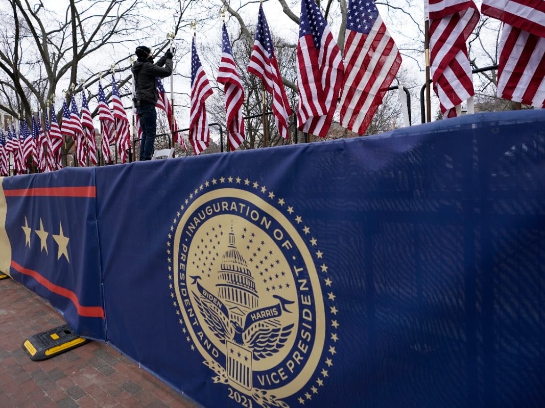 A worker installs flags on Pennsylvania Avenue in front of the White House ahead of President-elect Joe Biden's inauguration ceremony, Tuesday, Jan. 19, 2021, in Washington.