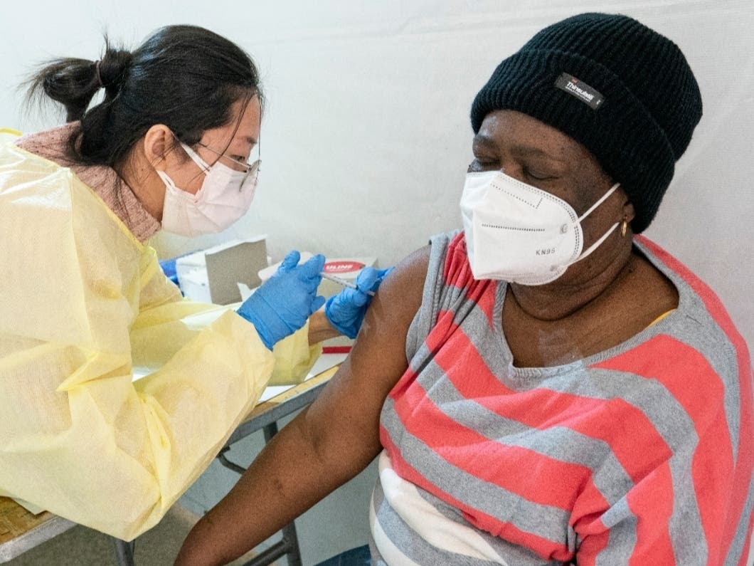 Registered Nurse Shyun Lin, left, administers Alda Maxis, 70, the first dose of the COVID-19 vaccine at a pop-up vaccination site in the William Reid Apartments in the Brooklyn borough of New York. 