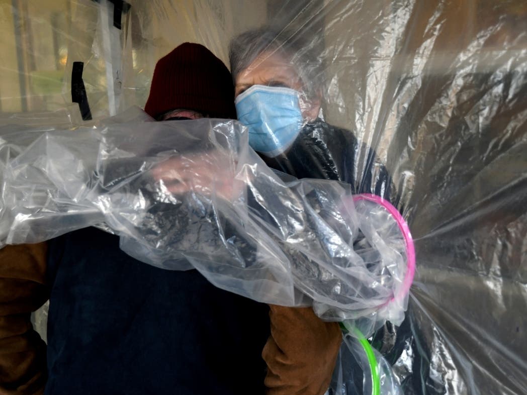 Lynda Hartman, 75, embraces her 77-year-old husband, Len Hartman, who suffers from dementia in a "hug tent" set up outside the Juniper Village assisted living center in Louisville, Colo.