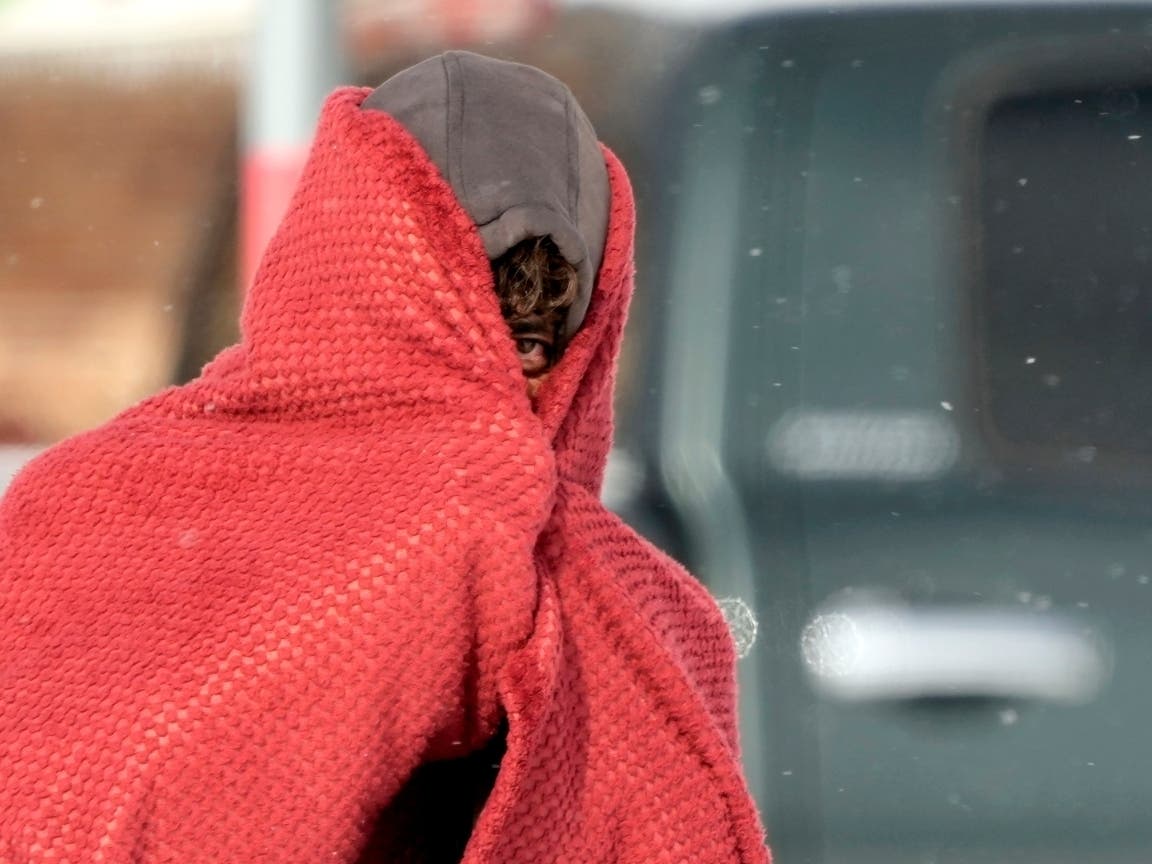 A man peers out from under a blanket while trying to stay warm in below freezing temperatures Monday, Feb. 15, 2021, in Houston. 