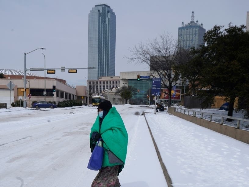 A woman wrapped in a blanket crosses the street near downtown Dallas.