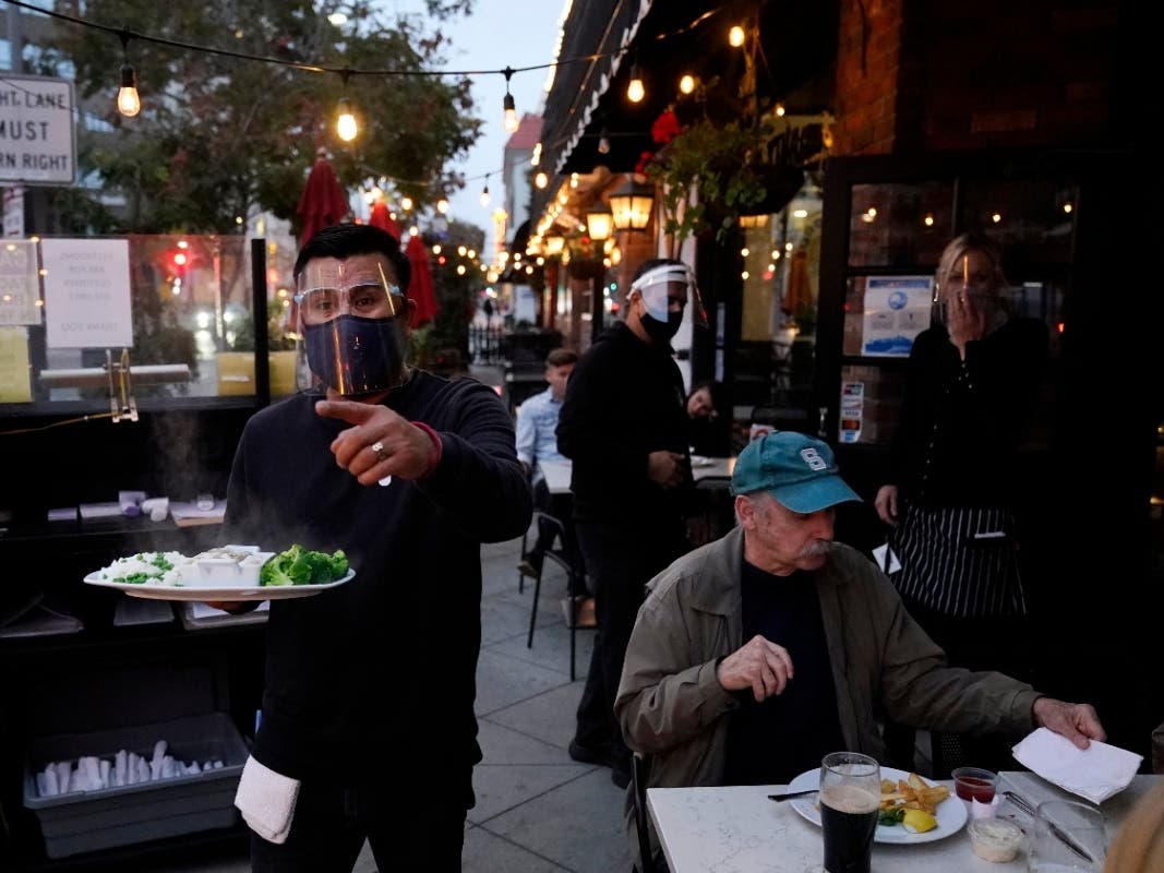A server carries food for a customer at Ye Olde King's Head in Santa Monica, California. Not willing to wait for more federal help, states, like California, have been moving ahead with their own coronavirus relief packages.