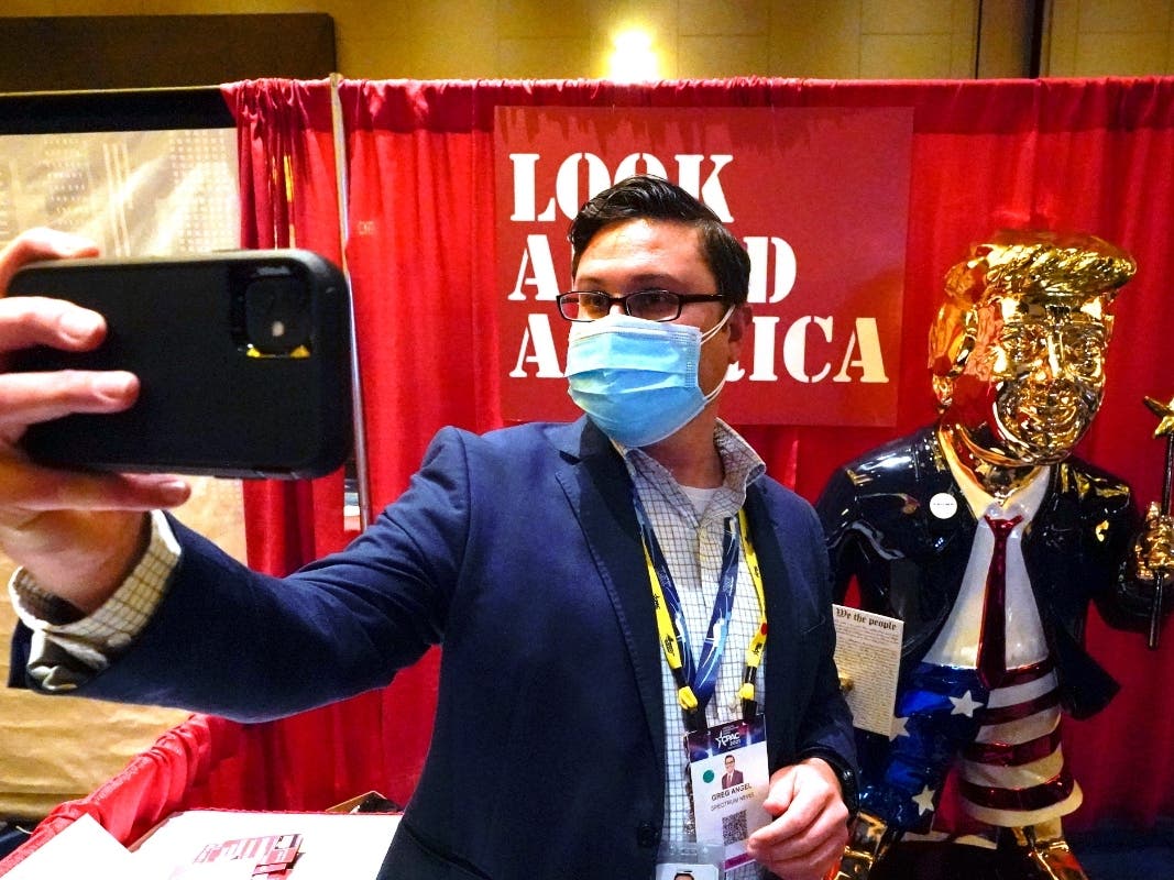 A conference attendee takes a selfie photo in front of a statue of former president Donald Trump at the Conservative Political Action Conference in Orlando, Florida.