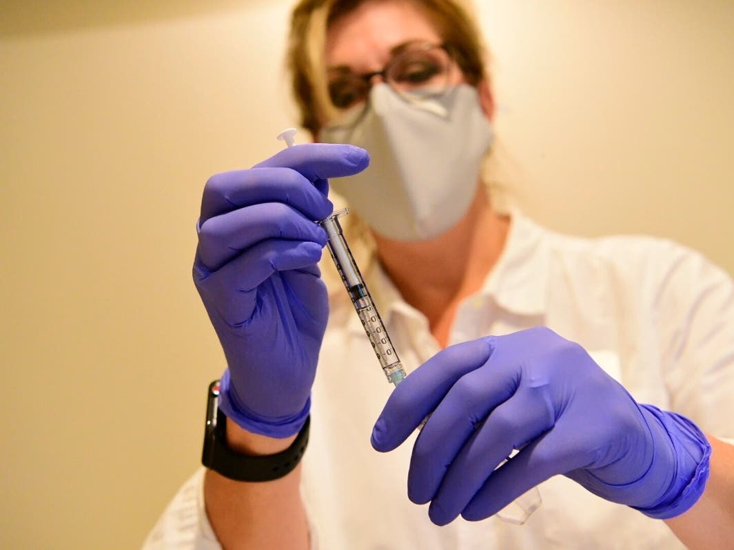 A pharmacist prepares to give an experimental COVID-19 vaccine. 