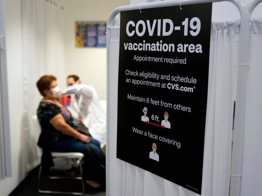 In this March 1, 2021, file photo, a patient receives a shot of the Moderna COVID-19 vaccine next to a guidelines sign at a CVS Pharmacy branch in Los Angeles. 