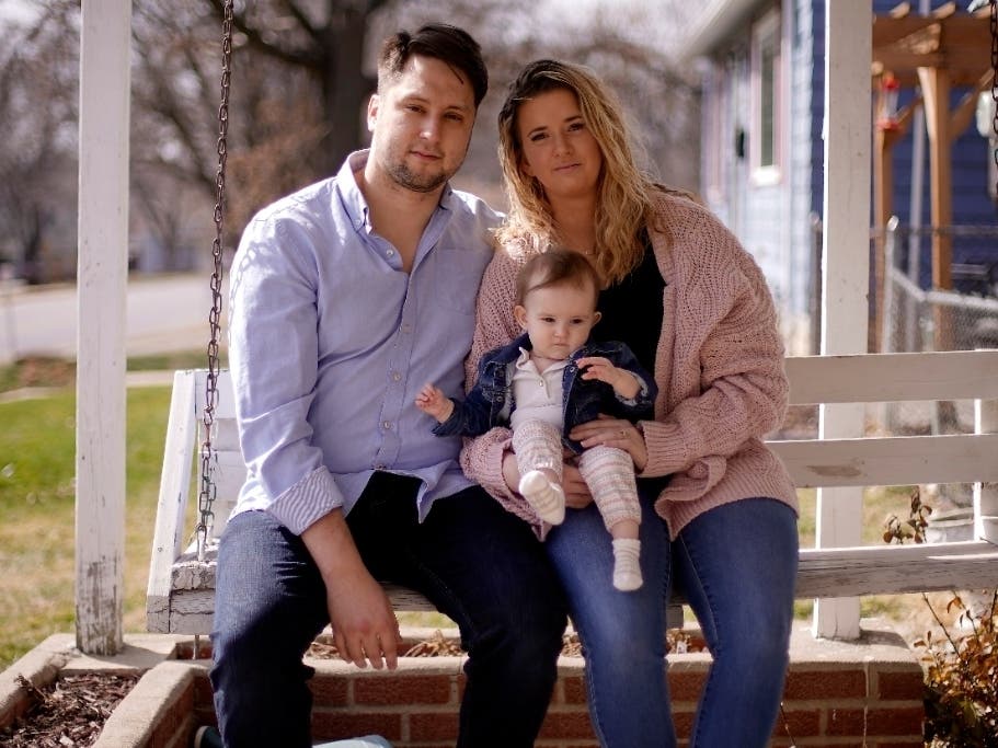 Logan DeWitt with his wife Mckenzie and daughter Elizabeth sit on the front porch of their home on Monday in Kansas City, Kansas. 