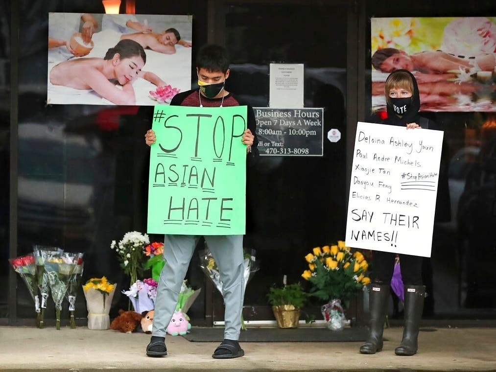 Jesus Estrella, left, and Shelby stand in support of the Asian and Hispanic communities outside Young's Asian Massage in Acworth, Georgia, Wednesday. Four people died in the shooting, the first of three  metro Atlanta massage parlor shootings Tuesday.