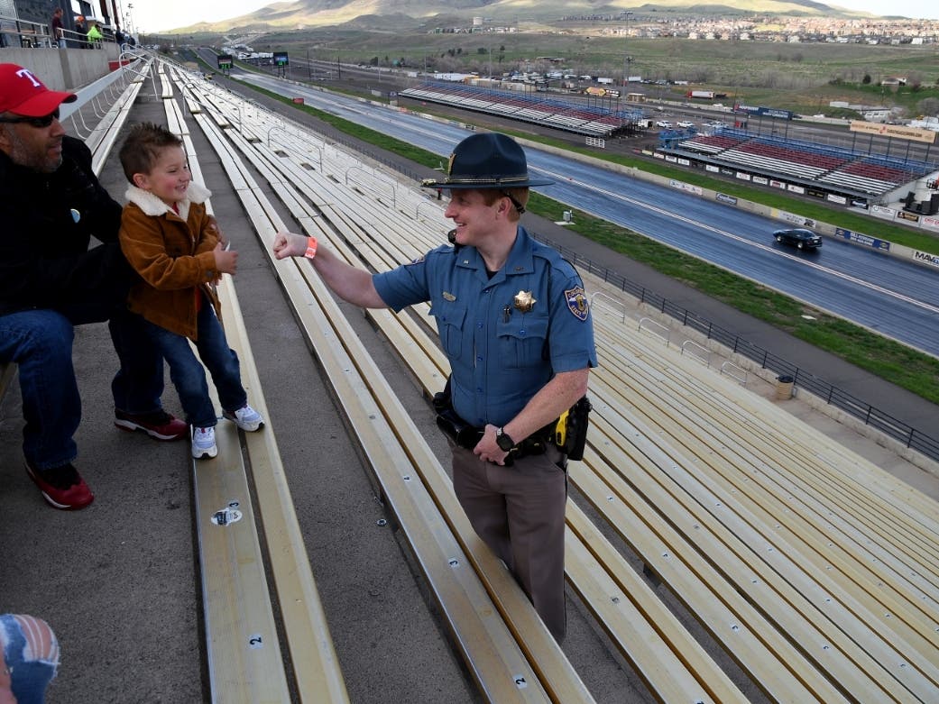 Colorado State Patrol Trooper Josh Lewis fist bumps 3-year-old Lincoln Delagarza, of Northglenn, before racing begins at Bandimere Speedway on May 5. The state patrol runs a program that aims to  lure racers away from public areas to a safer environment.