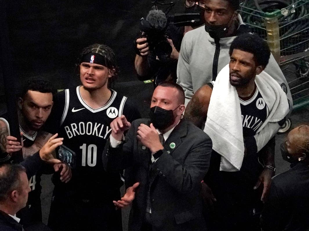 A security guard points as Brooklyn Nets' Kyrie Irving, right with towel, and teammates look up at a fan who reportedly threw a water bottle at him as he left the court after Game 4 