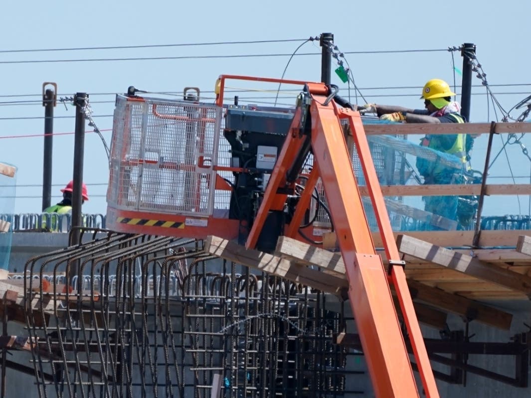A worker stands near a lift, Tuesday, June 29, 2021, as he works on a future Sound Transit light rail station near Federal Way, Wash., south of Seattle.