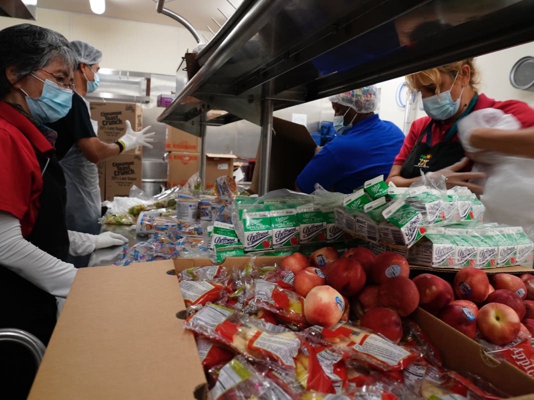 Los Angeles Unified School District food service workers from left, Tomoko Cho, Aldrin Agrabantes, April Thomas, and Marisel Dominguez, pre-package hundreds of free school lunches in plastic bags on Thursday, July 15, 2021.