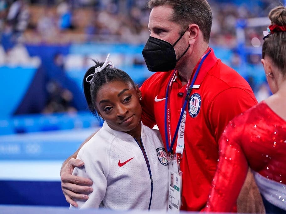 Coach Laurent Landi embraces Simone Biles, after she exited the team final with an apparent injury at the 2020 Summer Olympics.