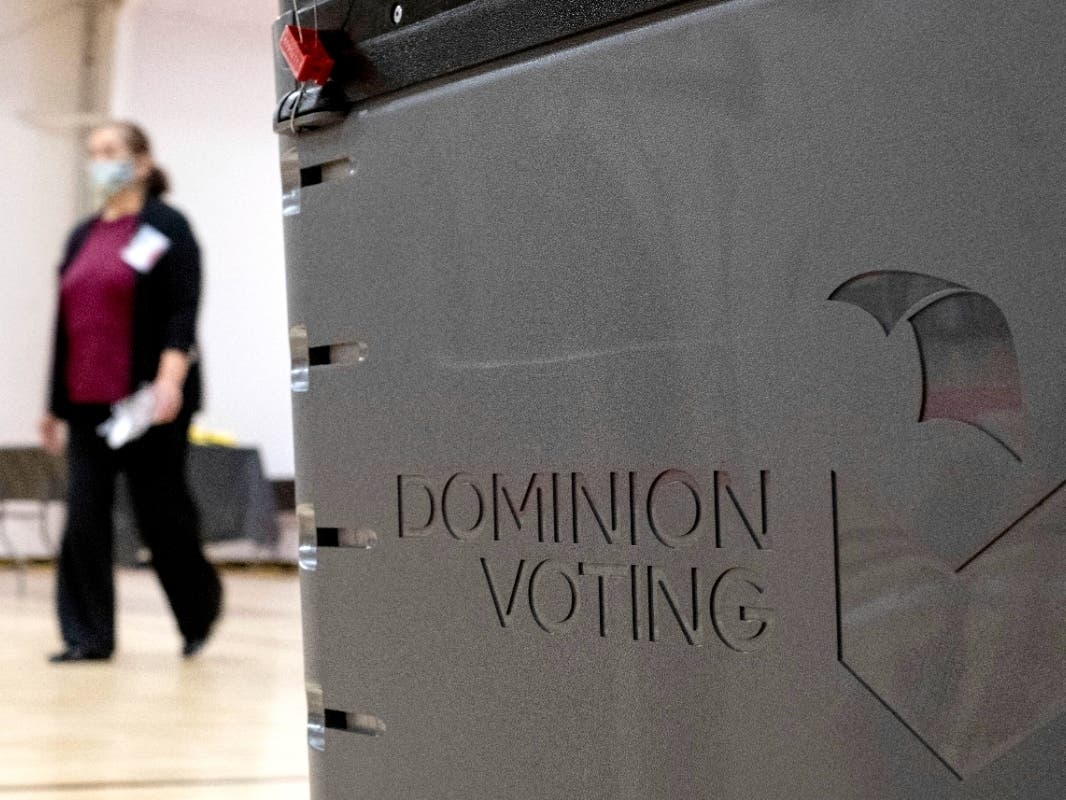 In this file photo, a worker passes a Dominion Voting ballot scanner while setting up a polling location in Atlanta. A federal magistrate on Wednesday levied penalties against attorneys for filing a lawsuit that alleged the 2020 election was stolen.
