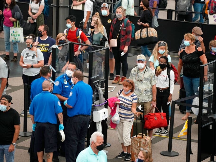 Travelers wear face coverings in the line for the south-north security checkpoint in the main terminal of Denver International Airport. The Biden administration this week rolled out new international travel policies for anyone flying into the U.S.