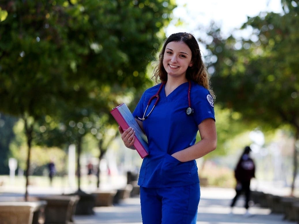 First year nursing student, Emma Champlin, poses for a photo near her class at Fresno State on Wednesday, Oct. 13, 2021, in Fresno, Calif. Nurses around the U.S. are getting burned out by the COVID-19 crisis and quitting, yet enrollment is rising.