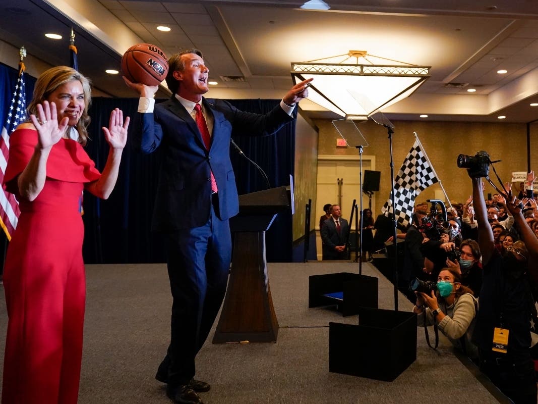 Virginia Gov.-elect Glenn Youngkin tosses a signed basketball to supporters as his wife, Suzanne, waves at an election night party in Chantilly, Virginia, early Wednesday after he  beat Democrat Terry McAuliffe, according to unofficial election results.