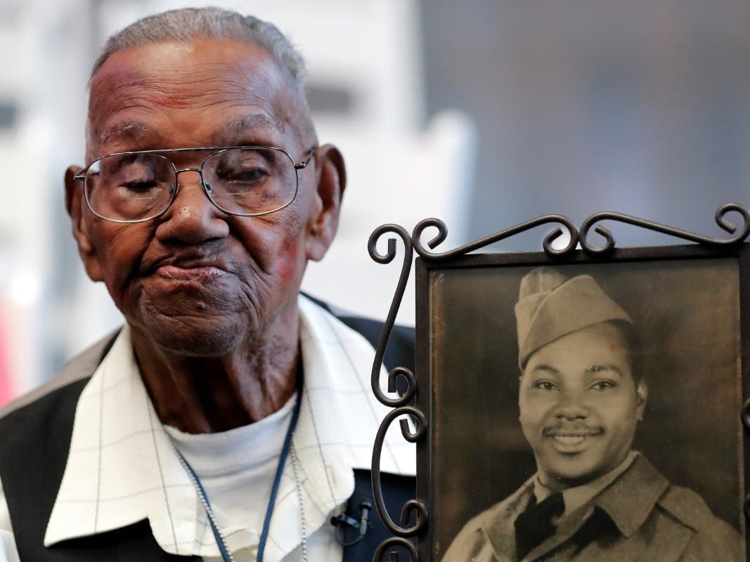 World War II veteran Lawrence Brooks holds a photo of him taken in 1943, as he celebrates his 110th birthday in 2019. A group of Democratic lawmakers, including Seth Moulton of Massachusetts, is reviving an effort to pay the families of Black servicemen.