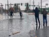 Caylon Coomes, second from left, and another man prepare to paddleboard in floodwaters on city streets in Bellingham, Wash., Monday, Nov. 15, 2021.