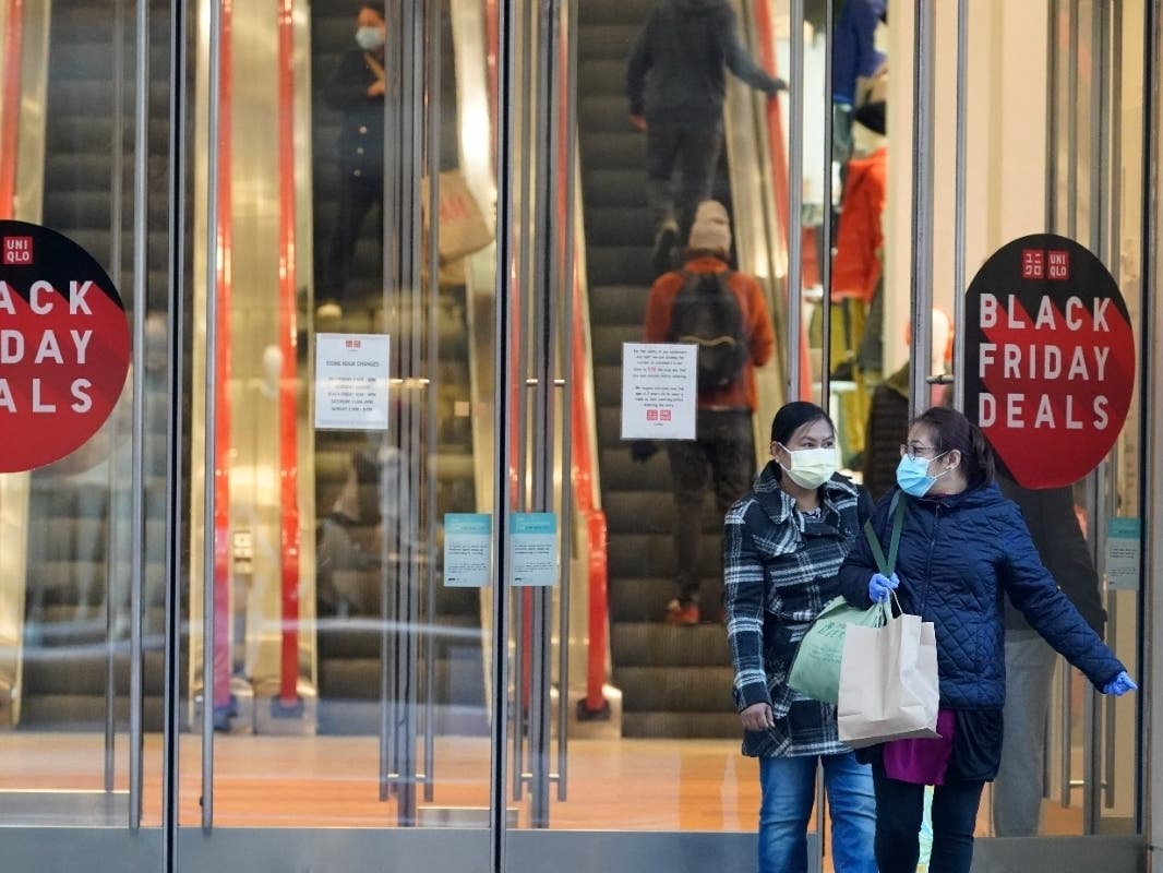 Last year, Black Friday shoppers wore face masks and gloves to protect themselves against the coronavirus as they left a Uniglo store in New York City. This year, Black Friday is expected to look a little more like it did in pre-pandemic years.