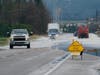 Vehicles drive through water over a road near Sumas, Wash., Monday, Nov. 29, 2021.