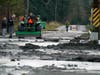 A tractor operator talks with people standing near a mud- and debris-covered road near Everson, Wash., Monday, Nov. 29, 2021.
