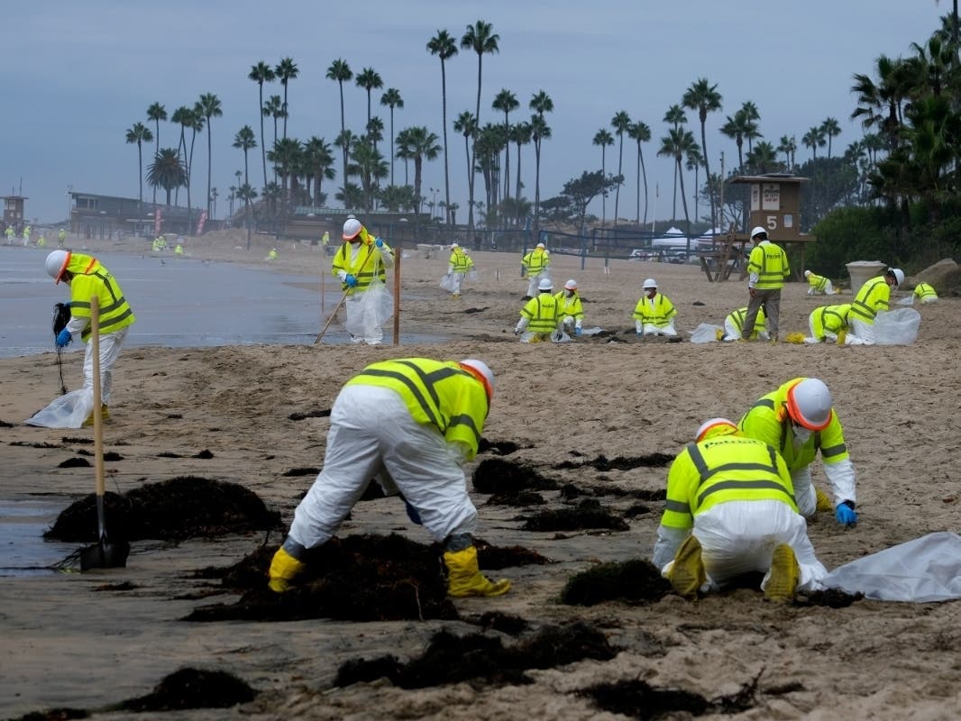 Workers in protective suits clean the contaminated beach in Corona Del Mar after an oil spill off the Southern California coast, on Oct. 7, 2021. 