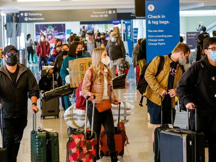 Holiday travelers wearing face masks line to check in at the Los Angeles International Airport in Los Angeles.