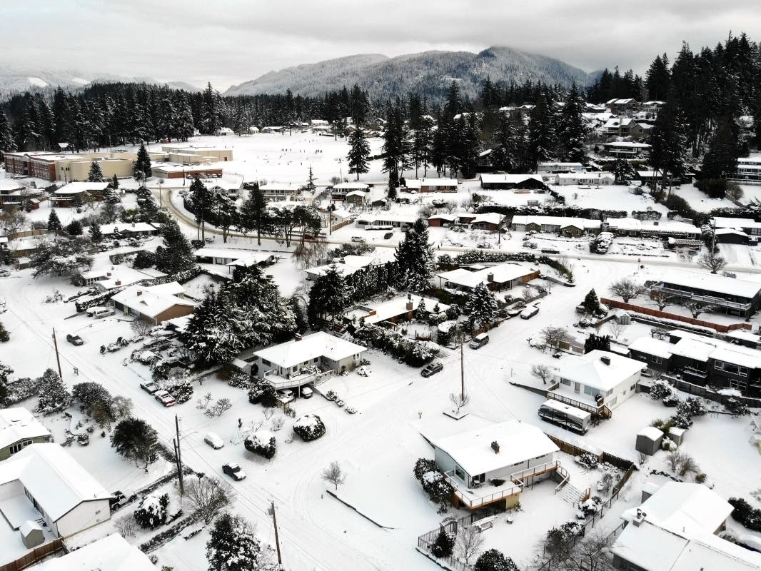 In this photo taken from a drone, snow covers streets, sidewalks and homes where nearly a foot of snow fell over the weekend, Monday, Dec. 27, 2021, in a neighborhood in Bellingham, Wash.