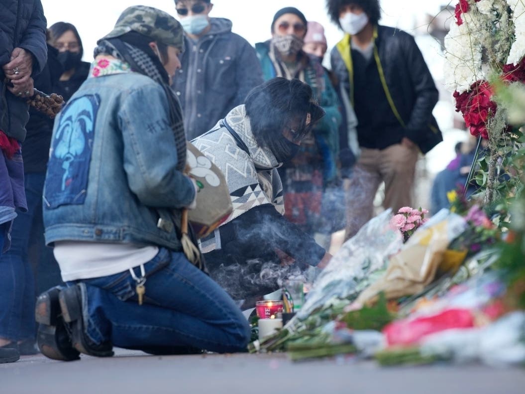 Mourners burn incense Tuesday as they gather outside the door of a tattoo parlor along South Broadway in Denver, one of the scenes of a shooting spree that left multiple people dead — including the suspected shooter Monday — and a few others wounded.