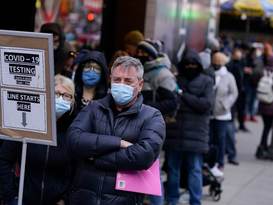 ​People wait in line at a COVID-19 testing site in New York's Times Square on Dec. 13. The fast-moving omicron variant is complicating a key question: How does the COVID-19 pandemic end and the world co-exist with this virus?